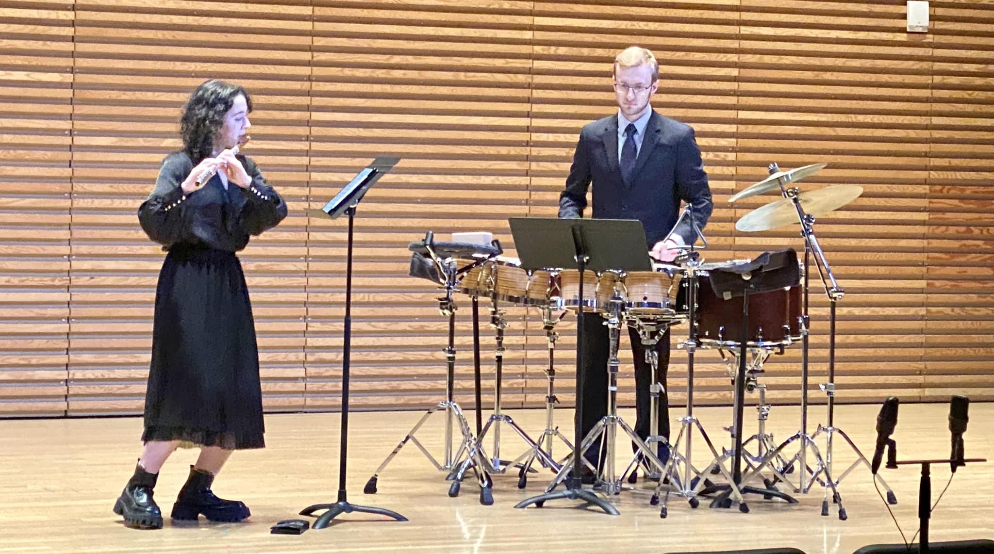Spencer Perilloux performing percussion with a flutist in a concert setting.
