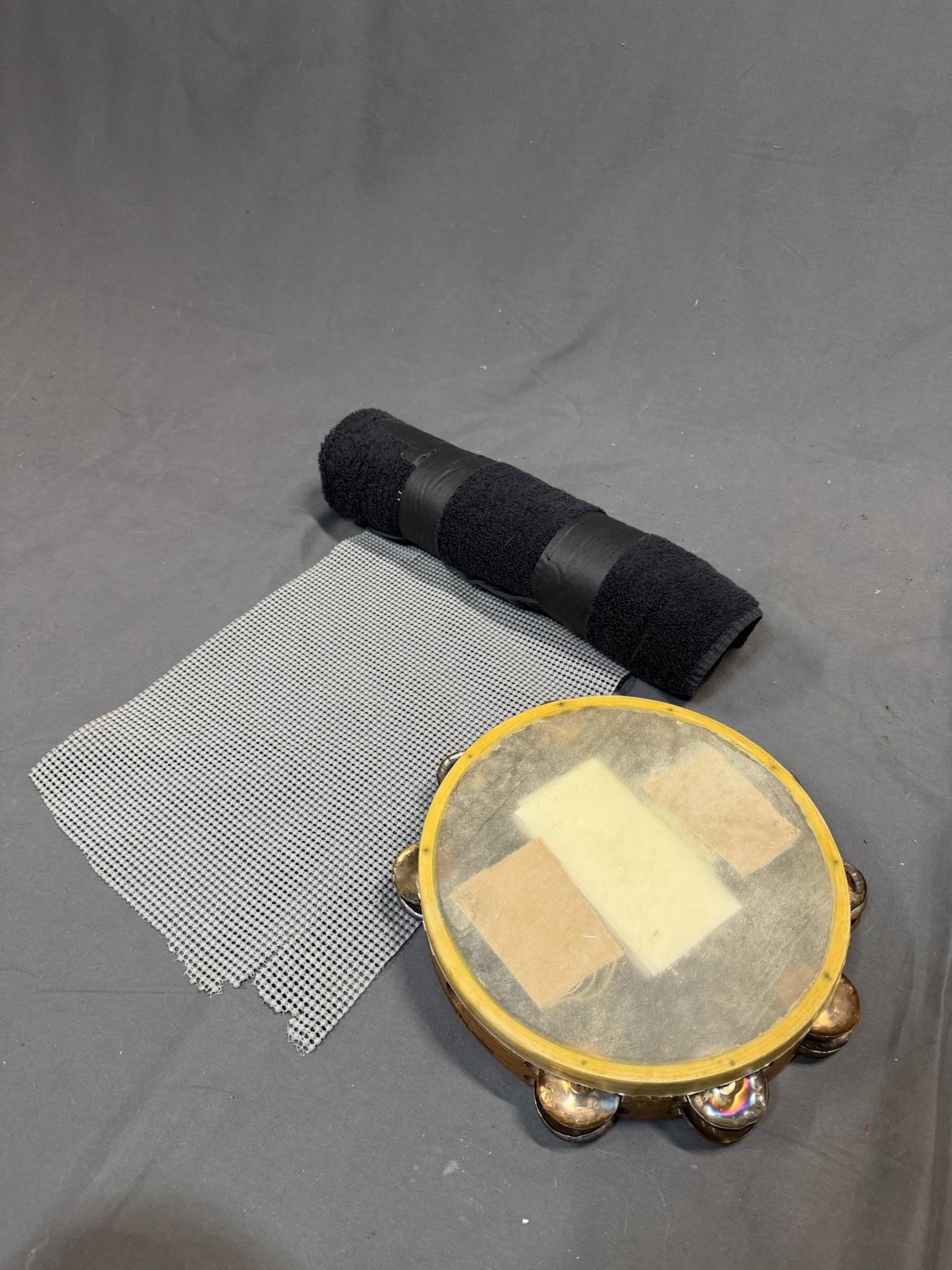 A completed TAM-BURRITO beside a tambourine and cabinet liner.