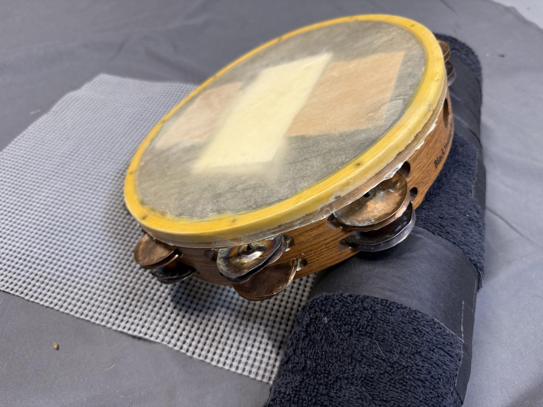 A tambourine resting between the towel roll and cabinet liner.