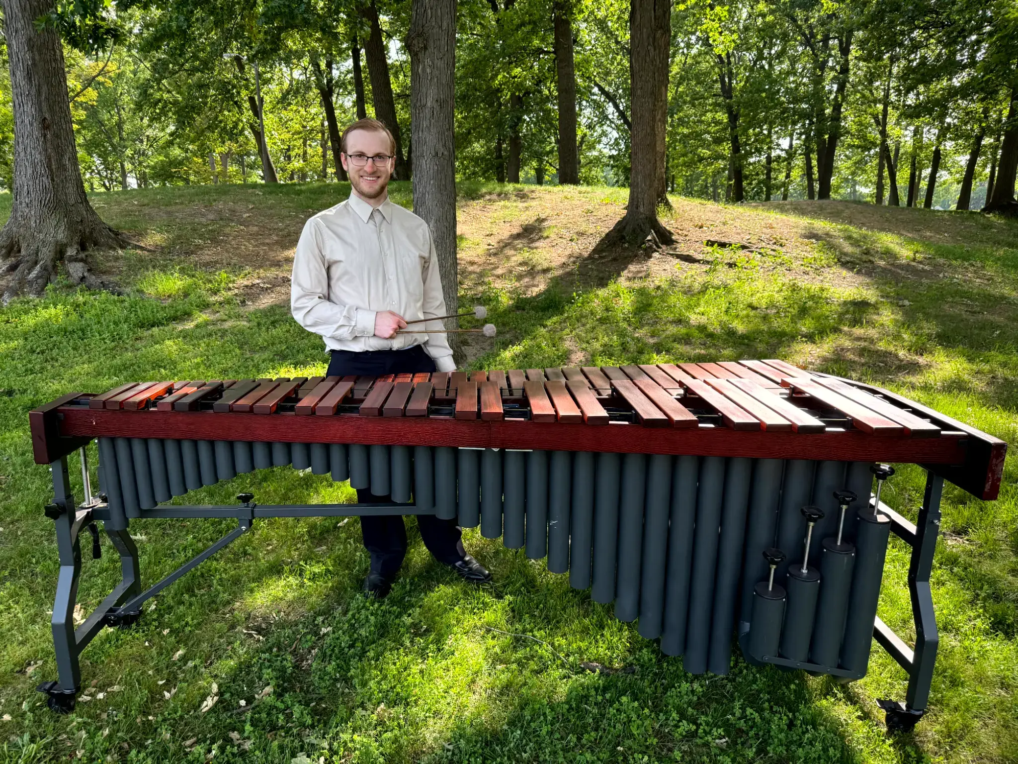 Spencer Perilloux with a marimba in a park setting.